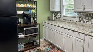 A kitchen with white cabinets, a black refrigerator, a microwave, and a coffee maker on a wooden shelf. - Bright and Airy 3 BRM - 1 BATH -5 Mins to Falls (Niagara Falls)