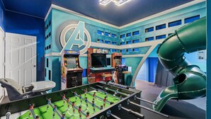 A room with a foosball table, arcade games, and a large A-shaped wall decoration. - 8BR Disney-Area Resort Home, Private Pool, Game Room | Sleeps 17,Lazy River-7054 (Davenport)
