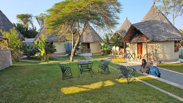 Thatched-roof huts with outdoor seating and a paved walkway.