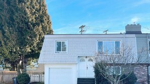A two-story house with a garage, a front yard, and a large tree. - Richmond Airport Cozy Holiday House with free shuttle (Richmond)
