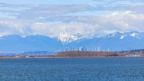 A city skyline with mountains in the background, a body of water in the foreground, and a distant shoreline with trees. - Richmond Airport Cozy Holiday House with free shuttle (Richmond)