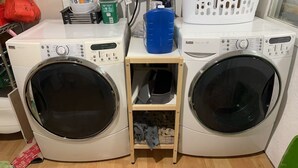 Two front-loading washing machines with a small wooden shelf between them. - Richmond Airport Cozy Holiday House with free shuttle (Richmond)