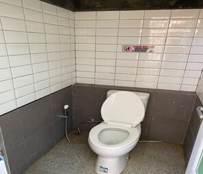 A small, tiled bathroom with a toilet, a hand sanitizer dispenser, and a sign warning against smoking. - Cozzy Saprag Riverside Pangalengan (BANDUNG)