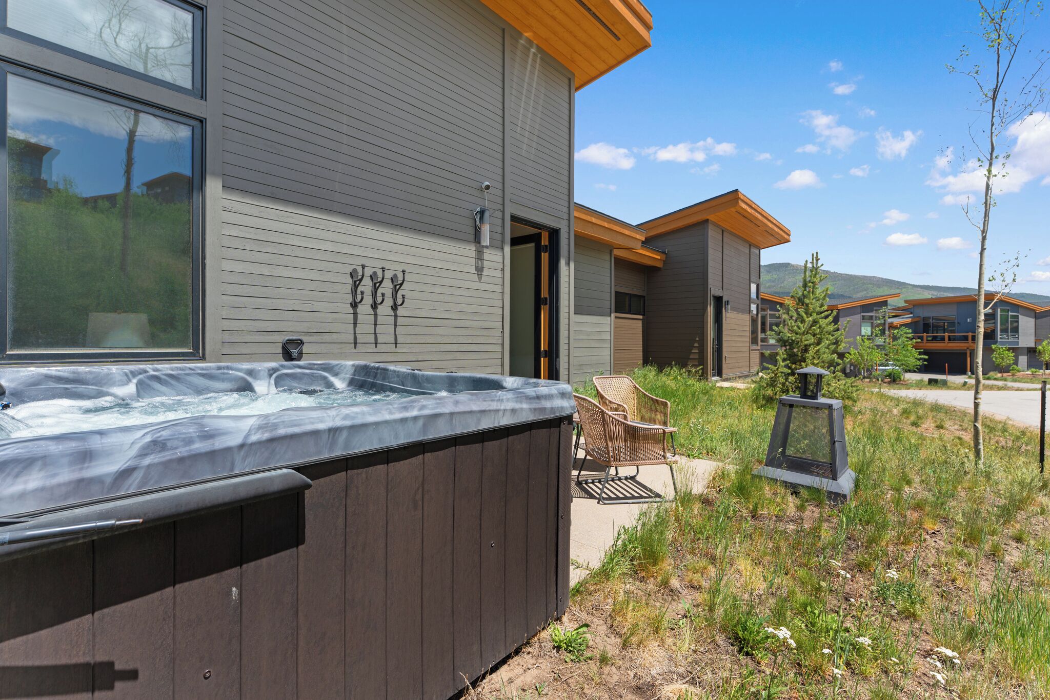 A modern building with a hot tub, outdoor seating, and a clear sky.