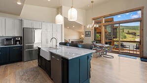 Una cocina moderna con una isla central, electrodomésticos de acero inoxidable y un comedor con vistas al exterior.