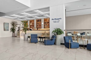 A modern lobby with a reception desk, seating area, and a bar. - Ocean View 2BR | Free Parking | Prime Location (Surfers Paradise)