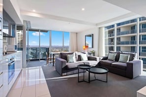 A modern apartment with a large balcony, a kitchen, and a living area with two sofas and a coffee table. - Ocean View 2BR | Free Parking | Prime Location (Surfers Paradise)
