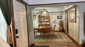 A dining area with a wooden table and chairs, a chandelier, and a patterned rug. - Elegant & Classic (South Hill Vibes) (Spokane)