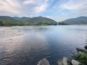 A river with a bridge in the distance, surrounded by hills and trees. - Sandman Motel (Hinton)