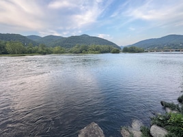 Un río con un puente a lo lejos, rodeado de colinas y árboles.