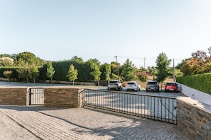 A paved driveway leading to a gated parking area with several cars parked.