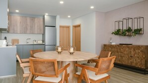 Una cucina moderna con mobili in legno, un tavolo da pranzo rotondo con sei sedie e un forno integrato.