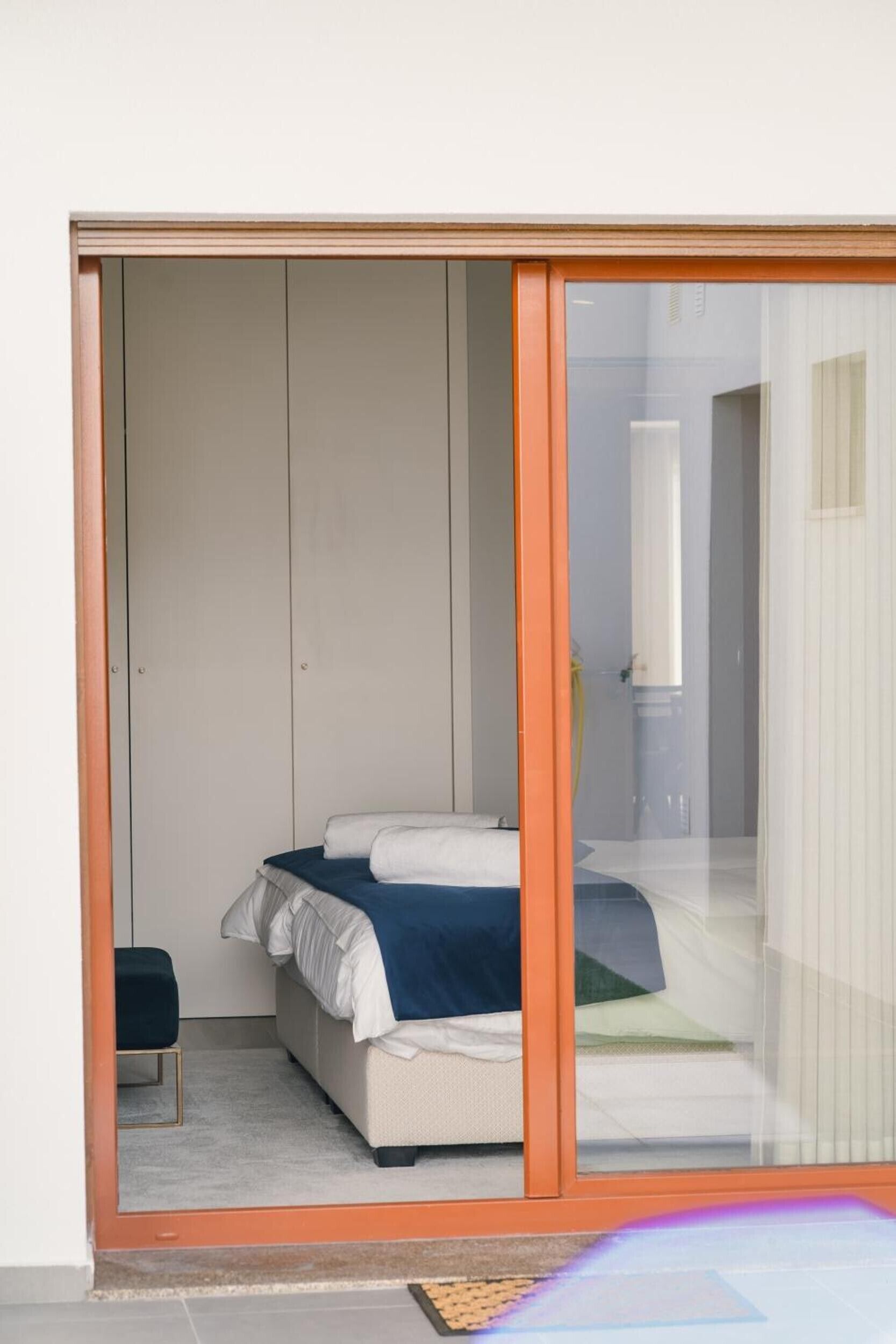 A bedroom with a bed, a chair, and a sliding door leading to another room.