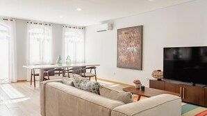 Un soggiorno moderno con divano, tavolo da pranzo con sedie, televisione e opere d'arte alle pareti.