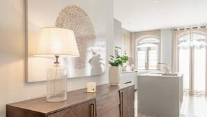 Una cucina moderna con isola centrale, un lampadario a sospensione e un grande quadro astratto appeso alla parete.