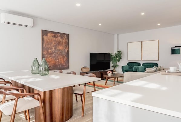 Ein modernes Wohnzimmer mit Fernseher, einem großen abstrakten Gemälde und einem grünen Sofa.