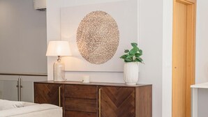 Un soggiorno moderno con divano, mobile contenitore in legno a spina di pesce, un'opera d'arte rotonda a parete, una lampada e una pianta in vaso.
