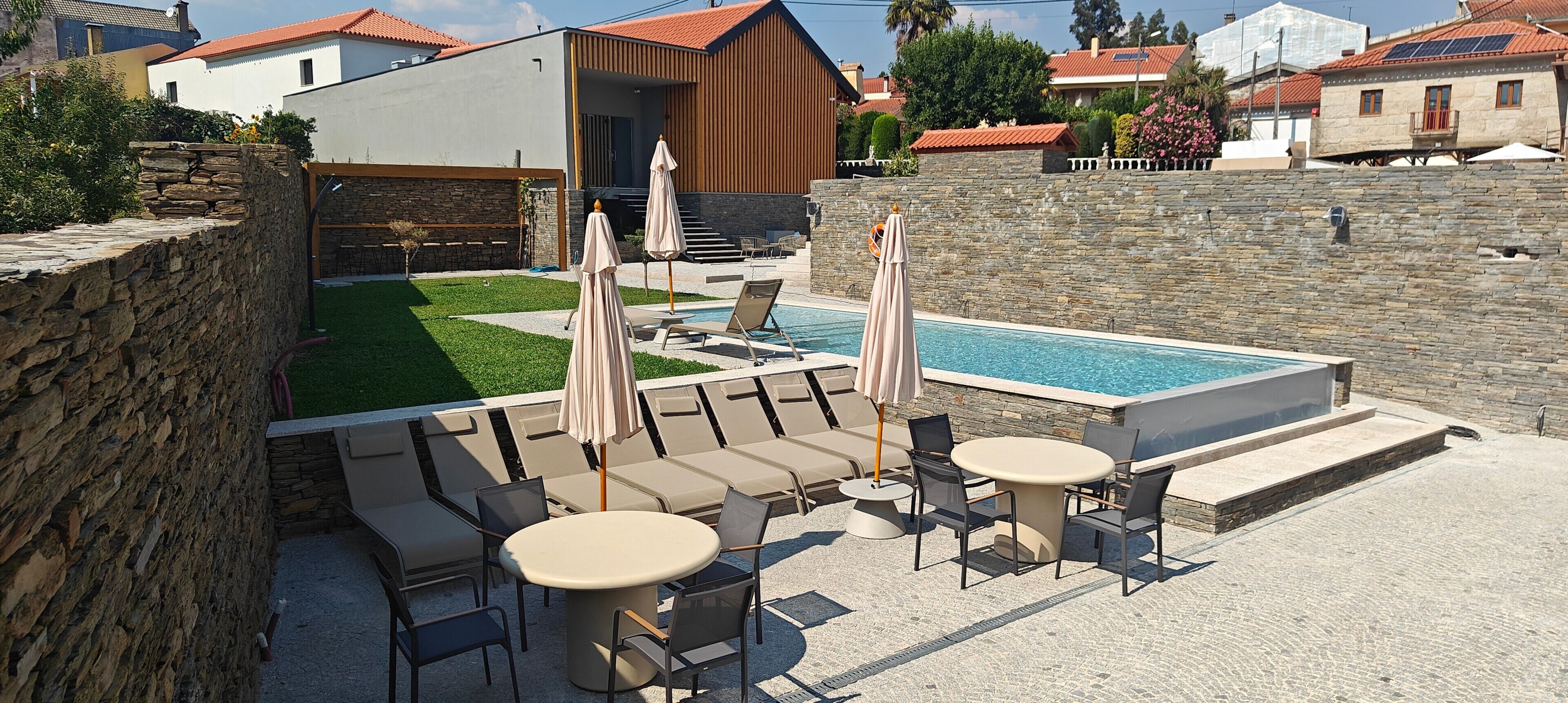 A poolside area with lounge chairs, umbrellas, and a table.
