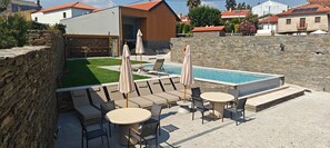 A poolside area with lounge chairs, umbrellas, and a table.