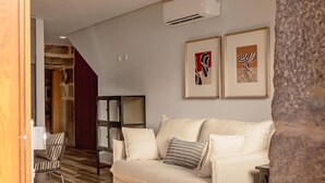 Un salon moderne avec un canapé blanc, une petite table en osier et un mur décoratif en pierre.