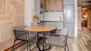 Une cuisine moderne avec une table ronde en bois et des chaises en métal noir, un mur en pierre et une cheminée en pierre.
