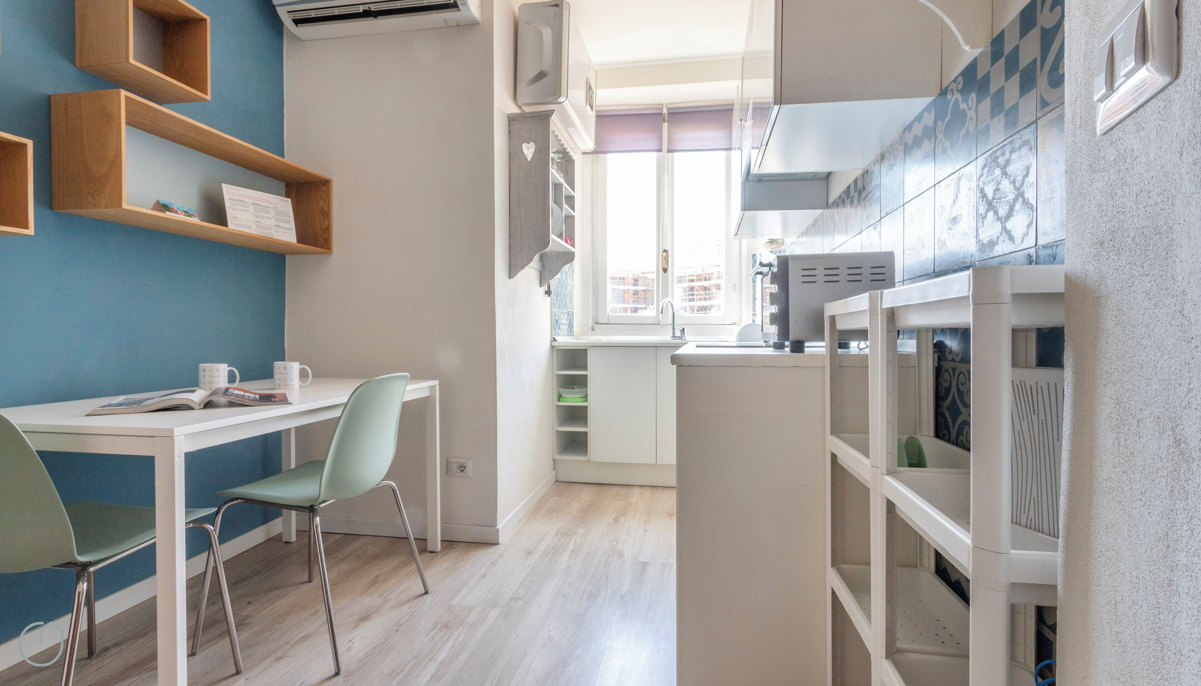 A modern kitchen with white cabinets, a built-in oven, and a window overlooking the city.