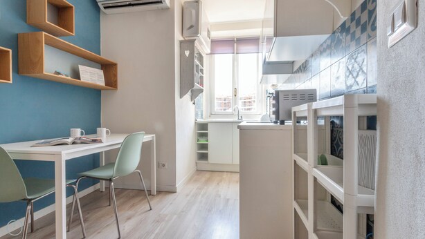 A modern kitchen with white cabinets, a built-in oven, and a window overlooking the city. - Italianway - San Calocero 29 B (Milano)