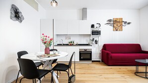 A compact living space with a dining area, kitchenette, and a red sofa. - Italianway Comfort - Boncompagni 3B (Milan)