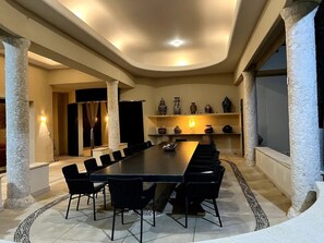 A conference room with a long table, black chairs, stone columns, and decorative vases on shelves. - Stunning luxury villa in the exclusive Tres Vidas development (Acapulco de Juárez)