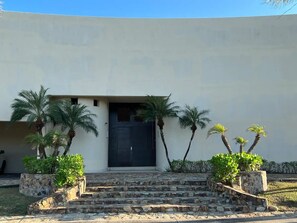 A building with a dark door, stone steps, and palm trees. - Stunning luxury villa in the exclusive Tres Vidas development (Acapulco de Juárez)