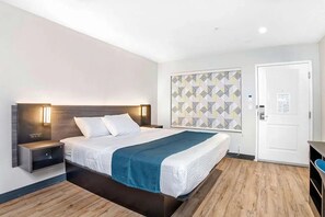 A modern hotel room with a bed, bedside tables, a patterned wall, and a door. - Explore Stockton’s Attractions from a Welcoming Retreat | Outdoor Pool Access (Stockton)