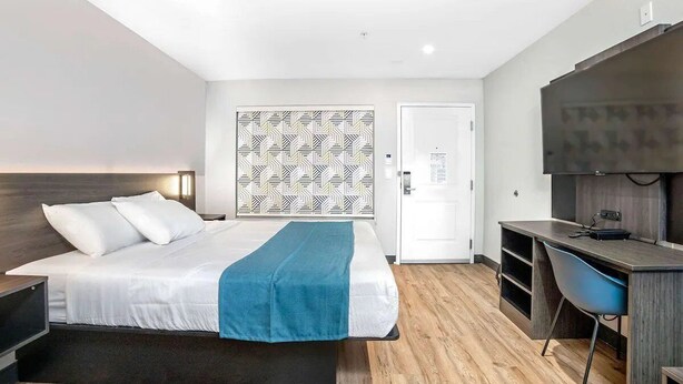 Una habitación de hotel moderna con cama, escritorio, silla y televisor.