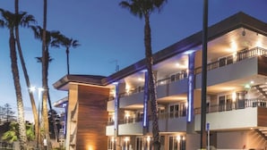 Un hotel de varios pisos con balcones, fachada de madera y palmeras.