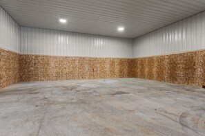 Una habitación amplia y vacía, con suelo de concreto y paneles de madera, que cuenta con un techo alto e iluminación empotrada.