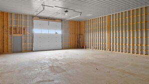 Um amplo espaço interior com pé-direito alto, estrutura de madeira aparente e chão de concreto.