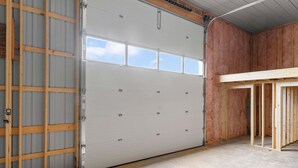 Garagem com porta branca grande, estrutura de madeira e piso de concreto.