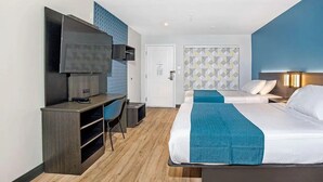 Une chambre d’hôtel comprenant un lit, un bureau avec une chaise, une télévision et une porte donnant sur une autre pièce.