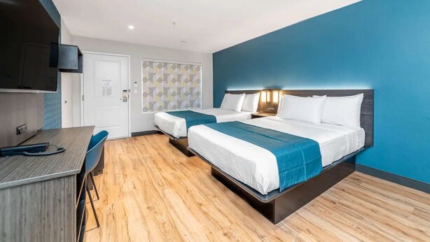 Une chambre d’hôtel avec deux lits, un bureau et une télévision.