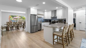 Une cuisine moderne dotée d’un îlot central, d’appareils électroménagers intégrés et d’un coin repas avec des chaises.