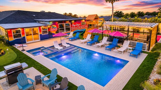 Une piscine avec des chaises longues et des parasols, un espace barbecue et un bâtiment sur lequel est apposée une enseigne indiquant « Seabreeze ».