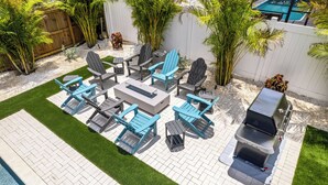 Une terrasse avec des meubles d’extérieur, un barbecue et une piscine.