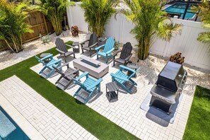 Eine Terrasse mit Gartenmöbeln, einem Grill und einem Pool.