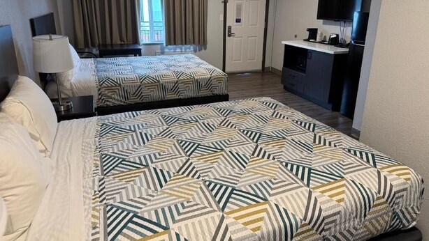 A hotel room with two beds, a desk, a television, and a door. - Efficient Extended Stay Retreat Near Vancouver Waterfront Park - 0.7 mile (Clark County)