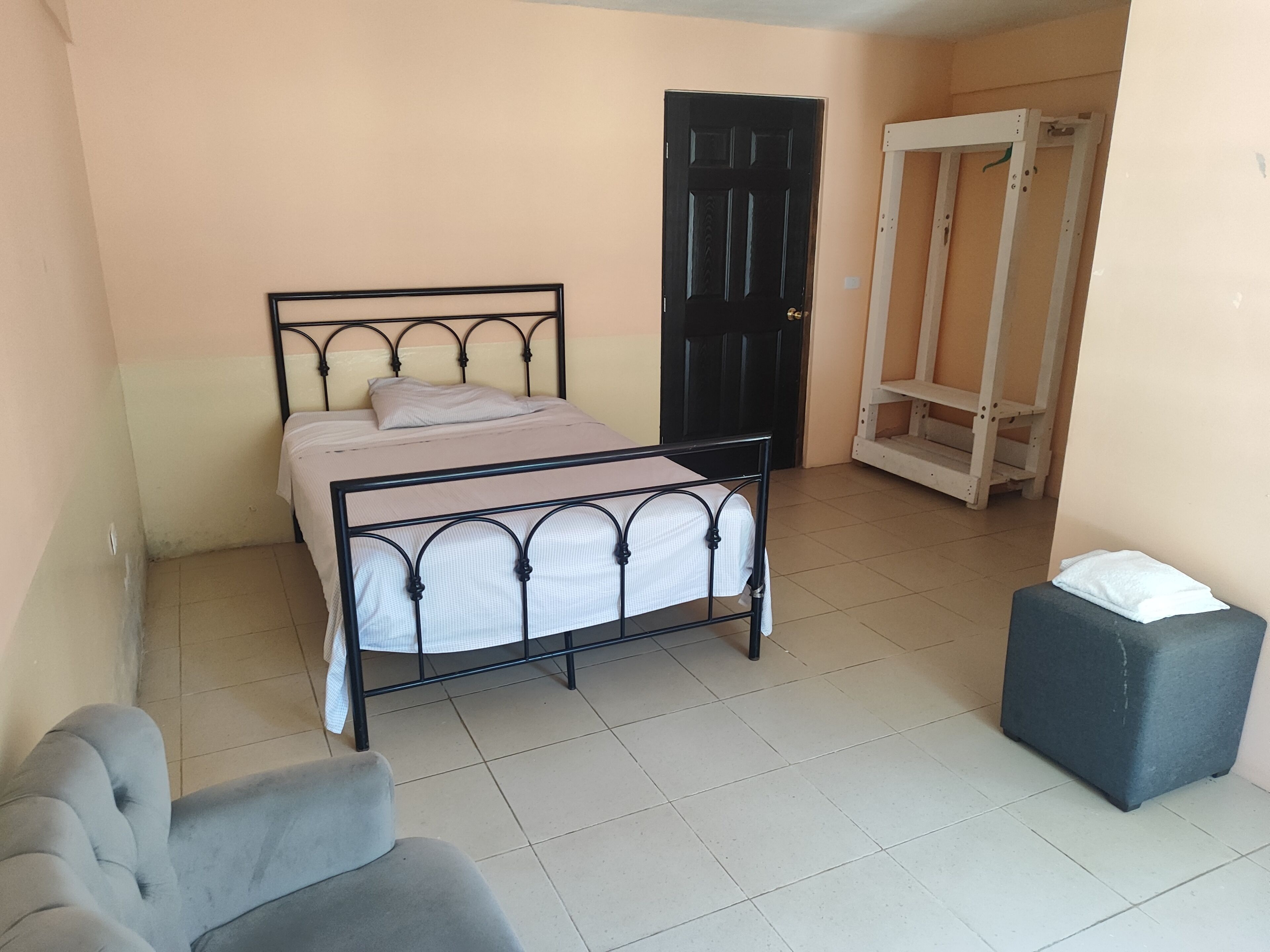 Un dormitorio con cama, una silla, armario y puerta.
