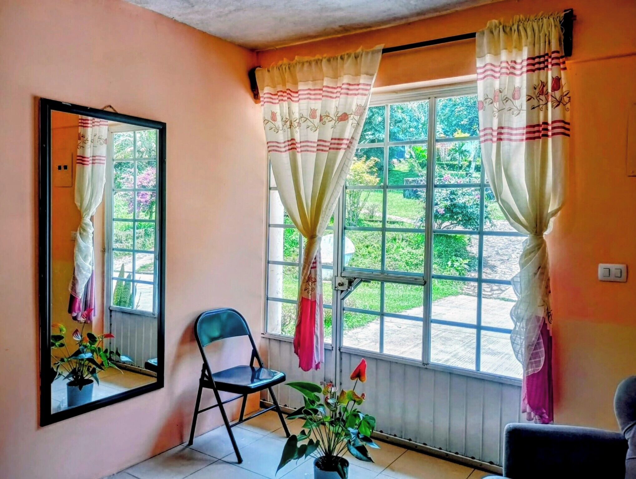 Una habitación con un ventanal grande, una silla y una planta en maceta.