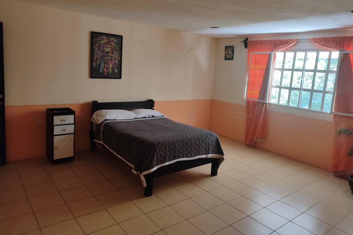 Een slaapkamer met een bed, een kaptafel, een raam met gordijnen en een schilderij aan de muur.