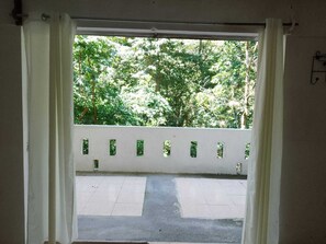 Puerta abierta con vistas a un balcón y árboles.
