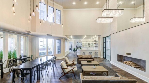 A spacious lounge area with a long table and chairs, a sofa, and a fireplace.