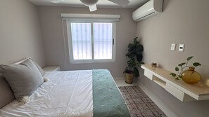 A bedroom with a bed, a window, a plant, and a shelf with a vase. - LOMA DEL MAR A19 PUERTO VALLARTA (Puerto Vallarta)