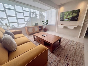 A modern living room with a sofa, coffee table, and a TV mounted on the wall. - LOMA DEL MAR A19 PUERTO VALLARTA (Puerto Vallarta)